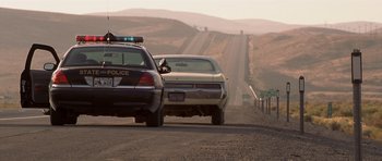 Movie still from “Joy Ride” (2001), directed by John Dahl – A police car and a car on the side of the road; Wide shot, Low angle