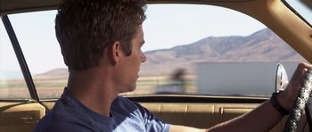 Movie still from “Joy Ride” (2001), directed by John Dahl – A young man driving a car in the middle of the day; Close Up shot, Over the shoulder angle