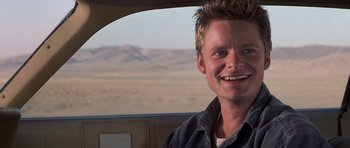 Movie still from “Joy Ride” (2001), directed by John Dahl – A man smiling while sitting in a car; Close Up shot, Low angle