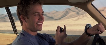 Movie still from “Joy Ride” (2001), directed by John Dahl – A man holding a cell phone while sitting in a car; Close Up shot, Over the shoulder angle