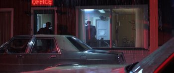 Movie still from “Joy Ride” (2001), directed by John Dahl – A man standing in a doorway next to a car; Wide shot, Low angle