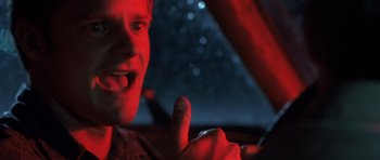 Movie still from “Joy Ride” (2001), directed by John Dahl – A man giving a thumbs up while driving a car at night; Close Up shot, Low angle
