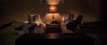 Movie still from “Joy Ride” (2001), directed by John Dahl – Two men sitting in chairs in a room with a lamp on; Wide shot, High angle