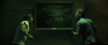 Movie still from “Joy Ride” (2001), directed by John Dahl – Two people are looking at a painting in a dark room; Wide shot, High angle