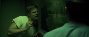 Movie still from “Joy Ride” (2001), directed by John Dahl – A man looking into a mirror with a boat in the background; Medium shot, High angle