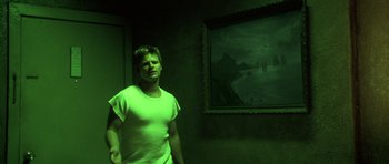 Movie still from “Joy Ride” (2001), directed by John Dahl – A man standing in front of a painting in a dark room; Medium shot, Low angle