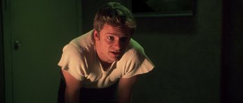 Movie still from “Joy Ride” (2001), directed by John Dahl – A young man is sitting in a dark room; Medium shot, Low angle