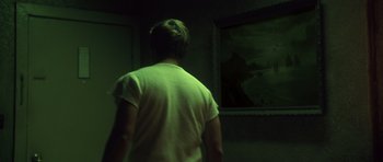 Movie still from “Joy Ride” (2001), directed by John Dahl – A man standing in front of a painting in a dark room; Wide shot, Over the shoulder angle