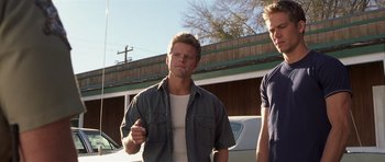 Movie still from “Joy Ride” (2001), directed by John Dahl – Two men standing next to each other in front of a building; Medium shot, Low angle