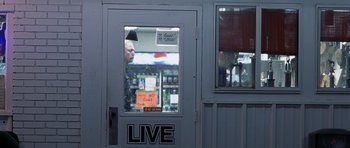Movie still from “Joy Ride” (2001), directed by John Dahl – A man standing in front of a store window; Wide shot, Over the shoulder angle