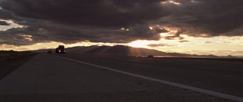 Movie still from “Joy Ride” (2001), directed by John Dahl – A car driving down a road under a cloudy sky; Extreme Wide shot, Low angle