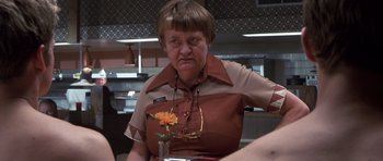 Movie still from “Joy Ride” (2001), directed by John Dahl – An older woman sitting at a table with a flower in a vase; Close Up shot, Over the shoulder angle