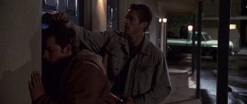 A man in a tan jacket is holding a cell phone