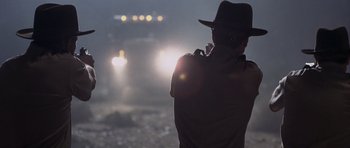 Movie still from “Joy Ride” (2001), directed by John Dahl – A man in a hat is standing in front of a street light; Medium shot, Low angle