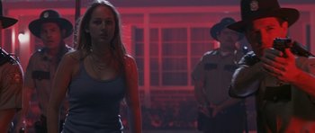Movie still from “Joy Ride” (2001), directed by John Dahl – A woman standing in front of a police officer in front of a building; Medium shot, Over the shoulder angle