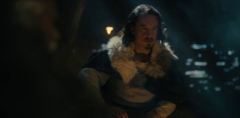 Movie still from “Barbarians” (2020), created by Arne Nolting – A man with long hair and a beard wearing a fur coat; Medium shot, Low angle
