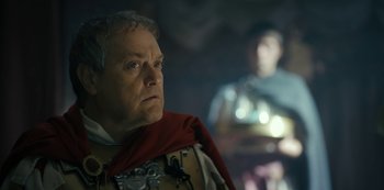 Movie still from “Barbarians” (2020), created by Arne Nolting – An older man wearing a red cape looking at the camera; Close Up shot, Low angle