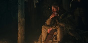 Movie still from “Barbarians” (2020), created by Arne Nolting – A man sitting on a chair in the dark; Medium shot, Low angle