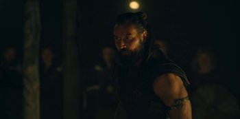 Movie still from “Barbarians” (2020), created by Arne Nolting – A man with long black hair and a beard; Close Up shot, Over the shoulder angle