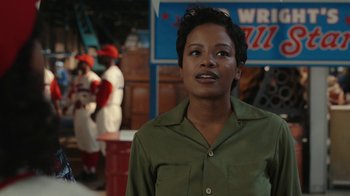 Movie still from “A League of Their Own” (2022), created by Abbi Jacobson – A woman standing in front of a crowd of people; Medium shot, Over the shoulder angle