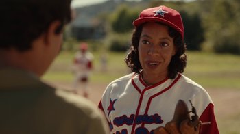 Movie still from “A League of Their Own” (2022), created by Abbi Jacobson – A woman in a baseball uniform holding a baseball glove; Close Up shot, Over the shoulder angle