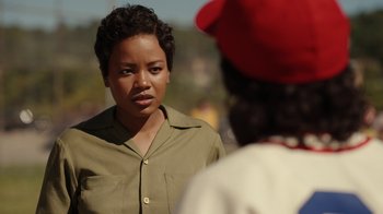 Movie still from “A League of Their Own” (2022), created by Abbi Jacobson – A woman standing next to another woman in a red hat; Close Up shot, Over the shoulder angle