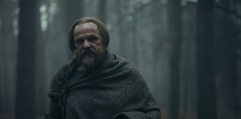 Movie still from “Barbarians” (2020), created by Arne Nolting – A man with a long beard and a blanket around his neck; Medium shot, Low angle