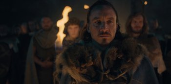 Movie still from “Barbarians” (2020), created by Arne Nolting – A man in a fur coat and a crowd of people behind him; Close Up shot, Low angle