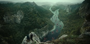 Movie still from “Barbarians” (2020), created by Arne Nolting – Two people are standing on a cliff looking down at a river; Extreme Wide shot, High angle