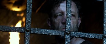 Movie still from “Pompeii” (2014), directed by Paul W.S. Anderson – A man looking through the bars of a jail cell; Close Up shot, Low angle