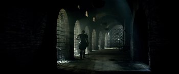 Movie still from “Pompeii” (2014), directed by Paul W.S. Anderson – A woman is walking through a dark room; Extreme Wide shot, Low angle