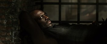 Movie still from “Pompeii” (2014), directed by Paul W.S. Anderson – A man laying on the ground in a dark room; Close Up shot, High angle