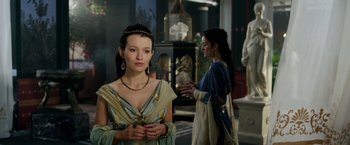 Movie still from “Pompeii” (2014), directed by Paul W.S. Anderson – A woman in a dress standing in front of another woman in a dress; Medium shot, Over the shoulder angle