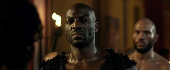 Movie still from “Pompeii” (2014), directed by Paul W.S. Anderson – A man with a beard is looking at the camera; Close Up shot, Low angle