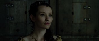 Movie still from “Pompeii” (2014), directed by Paul W.S. Anderson – A beautiful woman with long dark brown hair wearing a gold necklace; Close Up shot, Low angle