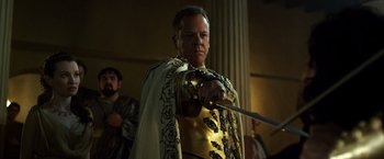 Movie still from “Pompeii” (2014), directed by Paul W.S. Anderson – A man dressed as a roman soldier holding a sword; Close Up shot, Over the shoulder angle