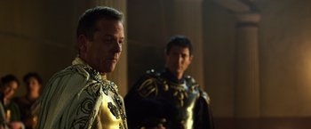 Movie still from “Pompeii” (2014), directed by Paul W.S. Anderson – Two men dressed in medieval garb standing next to each other; Close Up shot, Over the shoulder angle