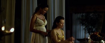 Movie still from “Pompeii” (2014), directed by Paul W.S. Anderson – Two women in white and yellow dresses one of whom is combing her hair; Medium shot, Over the shoulder angle