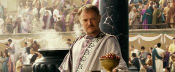 Movie still from “Pompeii” (2014), directed by Paul W.S. Anderson – A man in a roman outfit standing in front of a bowl of fruit; Medium shot, Over the shoulder angle