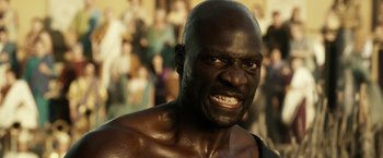 Movie still from “Pompeii” (2014), directed by Paul W.S. Anderson – A man's face with people in the background; Close Up shot, Low angle