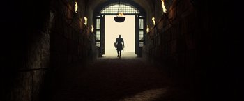 Movie still from “Pompeii” (2014), directed by Paul W.S. Anderson – A man walking down a hallway with a fire pit in front of him; Extreme Wide shot, Low angle