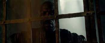 Movie still from “Pompeii” (2014), directed by Paul W.S. Anderson – A black man looking through the bars of a jail cell; Close Up shot, Low angle