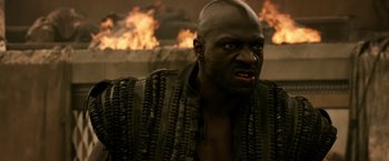 Movie still from “Pompeii” (2014), directed by Paul W.S. Anderson – A man with a black shirt is looking at the camera; Close Up shot, Low angle