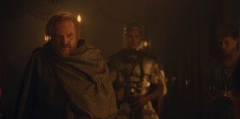 Movie still from “Barbarians” (2020), created by Arne Nolting – Two men dressed as roman soldiers in a dark room; Medium shot, Over the shoulder angle