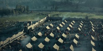 Movie still from “Barbarians” (2020), created by Arne Nolting – An aerial view of tents in the middle of a field; Extreme Wide shot, High angle
