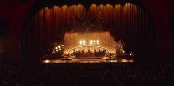 A stage with a band playing on it and people sitting in the seats watching