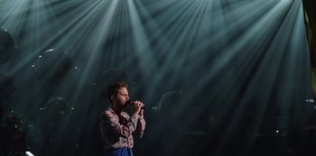 A man is singing into a microphone in front of a crowd