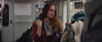 Movie still from “Berlin Syndrome” (2017), directed by Cate Shortland – A woman sitting on a train with a backpack; Medium shot, Over the shoulder angle