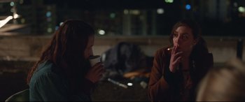 Movie still from “Berlin Syndrome” (2017), directed by Cate Shortland – Two people are sitting in a dark room drinking coffee; Medium shot, Over the shoulder angle