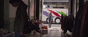 Movie still from “Berlin Syndrome” (2017), directed by Cate Shortland – A woman standing on the sidewalk in front of a bus; Wide shot, Over the shoulder angle